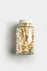 Transparent bottle with pills on white background, top view