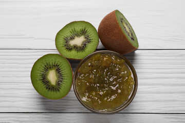 Jar with delicious kiwi jam and fresh fruits on white wooden table, flat lay