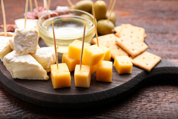 Toothpick appetizers. Pieces of different cheese on wooden table, closeup
