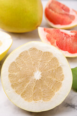 Different sorts of tasty pomelo fruits on white marble table, closeup