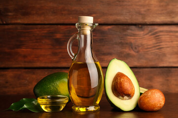 Cooking oil and fresh ripe avocados on wooden table