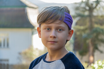 Street portrait of a boy with a bandana on his head on a neutral blurred background.
