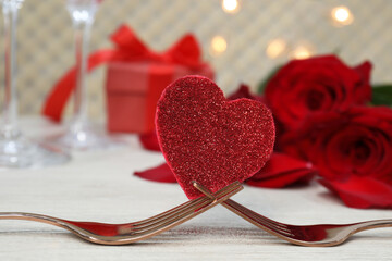 Forks and decorative heart on white table. Romantic place setting