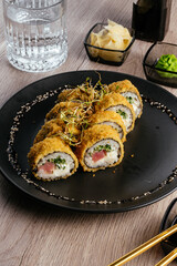 tempura sushi rolls on a black plate