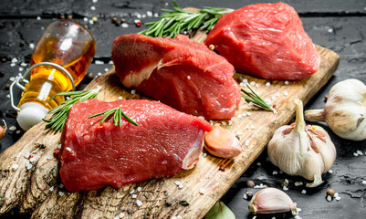 Raw meat. Sliced pieces of beef with spices and herbs on a wooden Board.