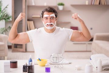 Young man shaving face at home