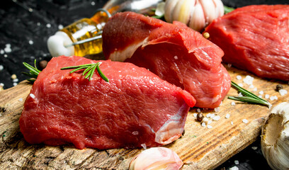 Raw meat. Sliced pieces of beef with spices and herbs on a wooden Board.