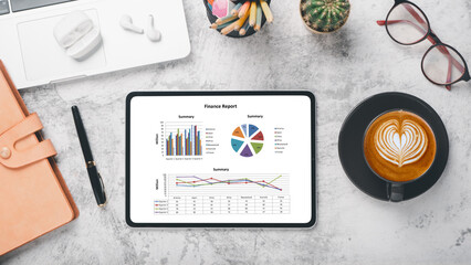Tablet with charts and reports on office desk workplace. Top view flat lay
