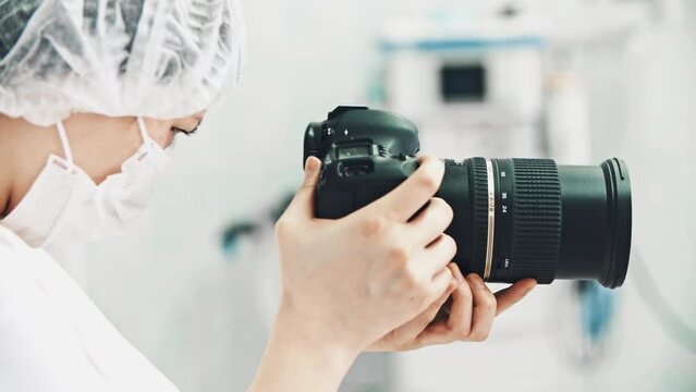 Woman operator portrait hold camera filming real surgical operation. Surgeon in protective costume in operating room. Hospital surgery emergency department. Concept of medicine, medicare healthcare.