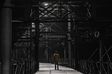 man with his back to the camera in the middle of the red pier at night.