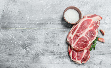 Raw pork steaks with salt.
