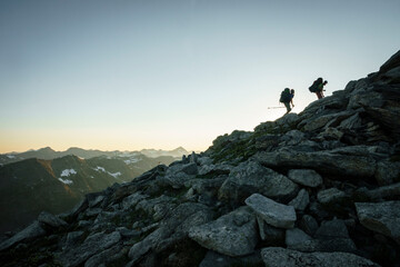 Silhouette of two male hikers at sunset with mountains in background