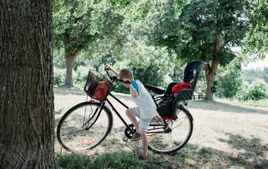 young boy looking at a big bike with a child seat