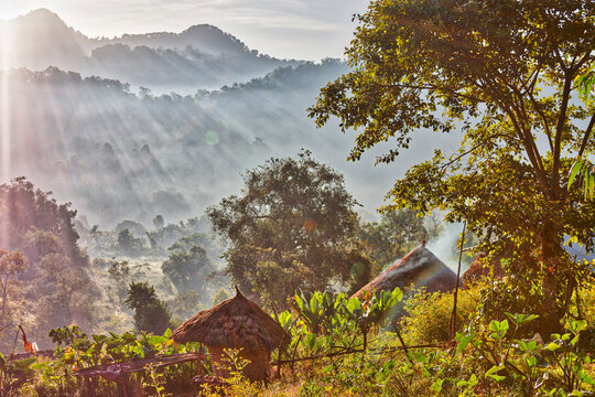 Thatched hut with silhouetted mountains in background during sunrise
