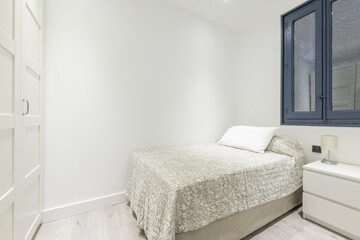 A bedroom with a double bed with a white wooden wardrobe and a blue wooden window