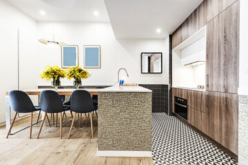 Studio apartment for vacation rental with an open kitchen with wooden units and white worktops and a dining table with blue chairs and chestnut flooring
