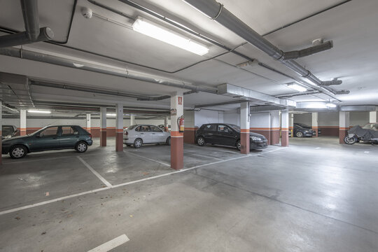 Ground floor of a building dedicated to a garage with a cement floor and spaces marked with white paint
