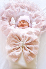 Fototapeta na wymiar Adorable newborn baby girl sleeping in pink warm envelope sleep bag