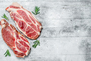 Raw pork steaks and fragrant rosemary.