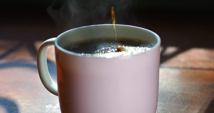 Tracking Close-up of steamy hot coffee poured into cup. 4K ProRes 422 HQ DCI 4096 x 2160. Shot on the Blackmagic Cinema Camera 6K Pro on a slider, with rack focus and natural morning light.