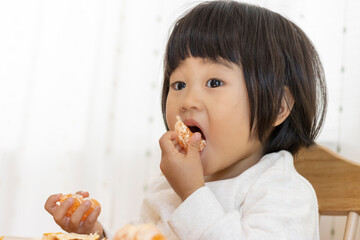 座ってミカンを食べる赤ちゃん（2歳4か月、女の子、日本人）
