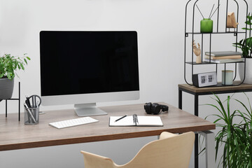 Cozy workspace with computer on desk near white wall at home