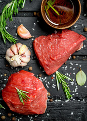 Raw meat. Sliced pieces of beef with spices and herbs on a wooden Board.