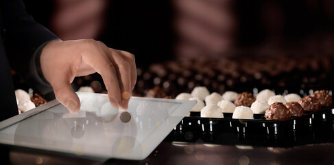 Production line of chocolate candies. Man working with tablet, closeup. Banner design