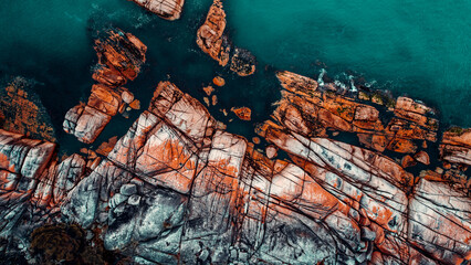 Drone Aerial of Orange Lichen Covered Boulders at Bay of Fires, Tasmania, Green Blue Water, Textured Boulders