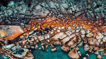 Drone Aerial of Orange Lichen Covered Boulders at Bay of Fires, Tasmania, Green Blue Water, Line Of Boilers