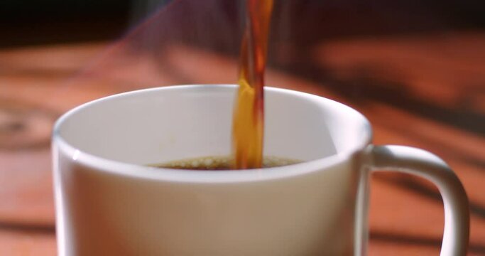 Tracking Close-up of steamy hot coffee poured into cup.   4K ProRes 422 HQ DCI 4096 x 2160.  Shot on the Blackmagic Cinema Camera 6K Pro on a slider, with rack focus and natural morning light. 