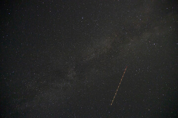 Satellite trail passing through the milky way, night-sky