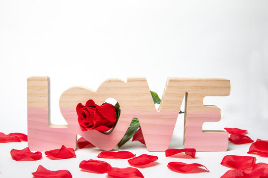 Word LOVE On Isolated White Background With A Red Rose. Red Rose Pedals  Around The Word. 