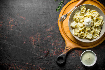 Dumplings with sour cream on a plate.