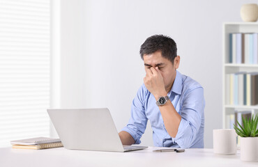 Overworked businessman eye strain after long laptop usage.