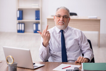 Obraz premium Old male employee working in the office