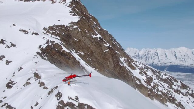 Heli-Skiing helicopter unloading gear on a snowy mountain in Alaska