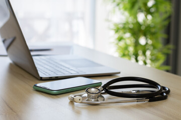 Medical stethoscope with laptop computer keyboard on doctor's office desk.