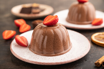 Chocolate jelly with strawberry on black concrete, side view, selective focus.