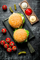 Burgers on the cutting Board and different sauces.