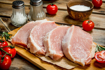 Raw pork steaks with tomatoes and rosemary.