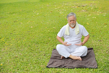 Fototapeta premium Asian senior man practice yoga exercise, stretching, tai chi tranining and meditation while sitting on yoga mat for healthy in park outdoor after retirement. Happy elderly outdoor lifestyle concept