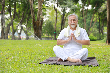 Naklejka na ściany i meble Asian senior man practice yoga exercise, stretching, tai chi tranining and meditation while sitting on yoga mat for healthy in park outdoor after retirement. Happy elderly outdoor lifestyle concept