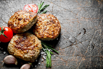 Cutlets with garlic cloves,rosemary and tomatoes.