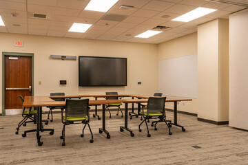 Interior of an office training, meeting, conference room with desks, chairs, and white board. ...