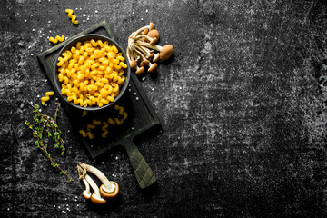 Raw pasta in bowl with mushrooms.