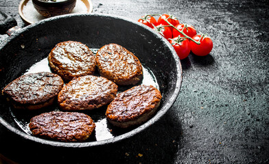 Cutlets in pan with spices and tomatoes.