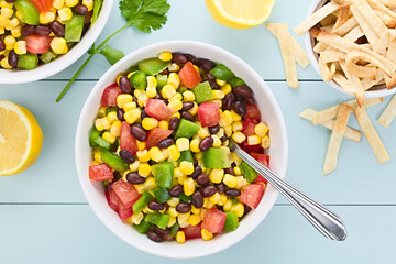 Mexican style colorful fresh vegetable salad made of beans, corn, tomato and bell pepper served in bowls, photographed overhead (Selective Focus, Focus on the salad)