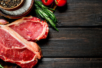 Raw beef steaks with salt and spices.