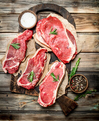 Raw marbled beef steaks with salt and aromatic spices.